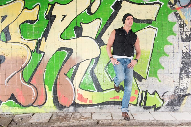 Portrait of a man standing in front of wall covered with graffiti