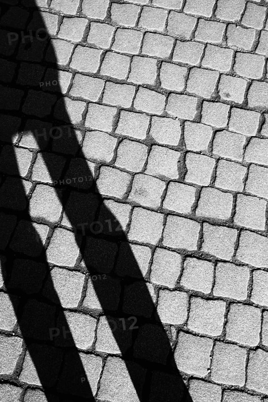 Shadow of a person on cobbled street