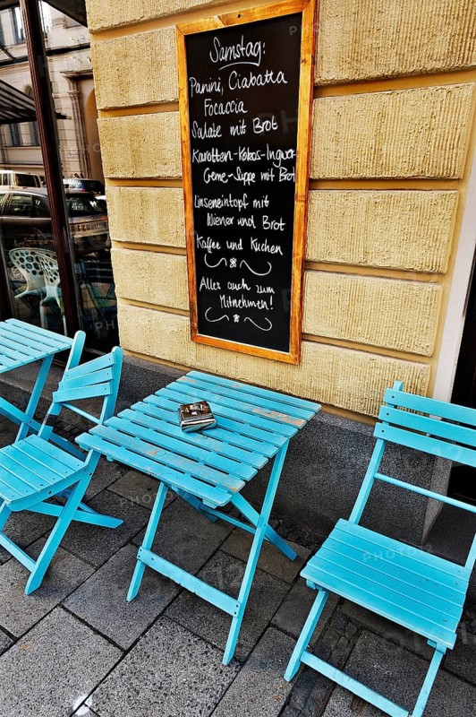Street cafe with a menu board and blue tables and chairs