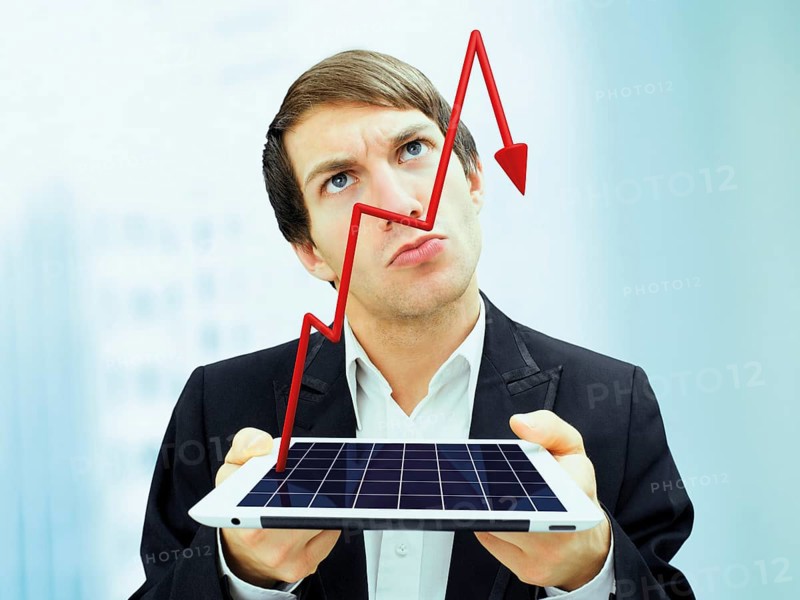 Businessman with a serious face holding an iPad with a plunging stock chart