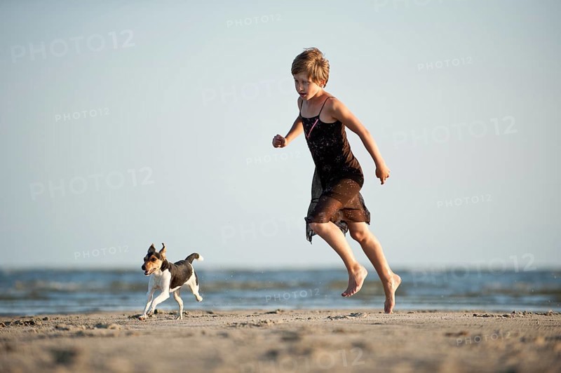 Girl running with a Dansk-Svensk Gardshund or Danish-Swedish Farmdog on the beach