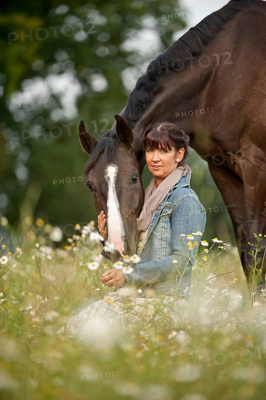 Woman standing beside a Hanoverian horse in a meadow