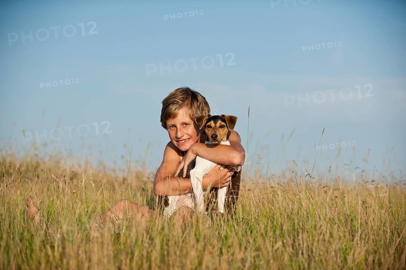 Girl sitting with a Dansk-Svensk Gardshund or Danish Swedish Farmdog in a meadow