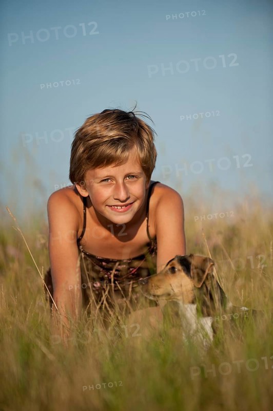 Girl sitting with a Dansk-Svensk Gardshund or Danish Swedish Farmdog in a meadow