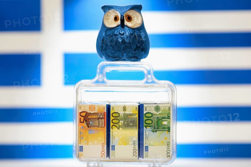 Owl on a suitcase full of money in front of a Greek flag