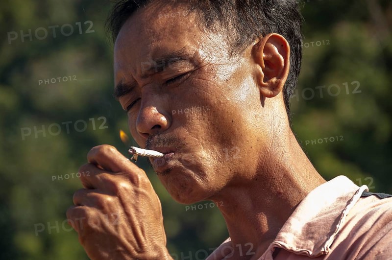 Man from the Shan or Thai Yai ethnic minority is lighting a cigarette