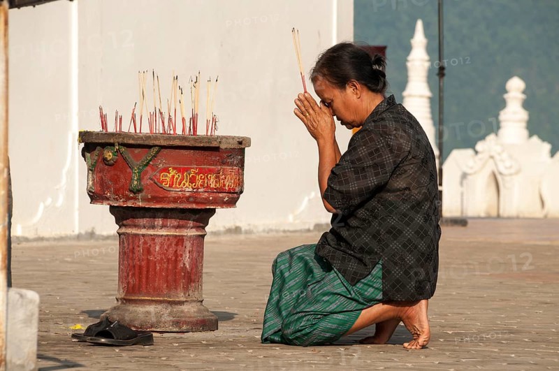 Woman in prayer holding incense sticks