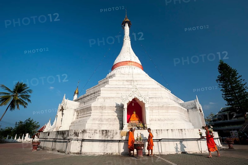 Young Buddhist monks with offerings in front of a Pagoda or Chedi
