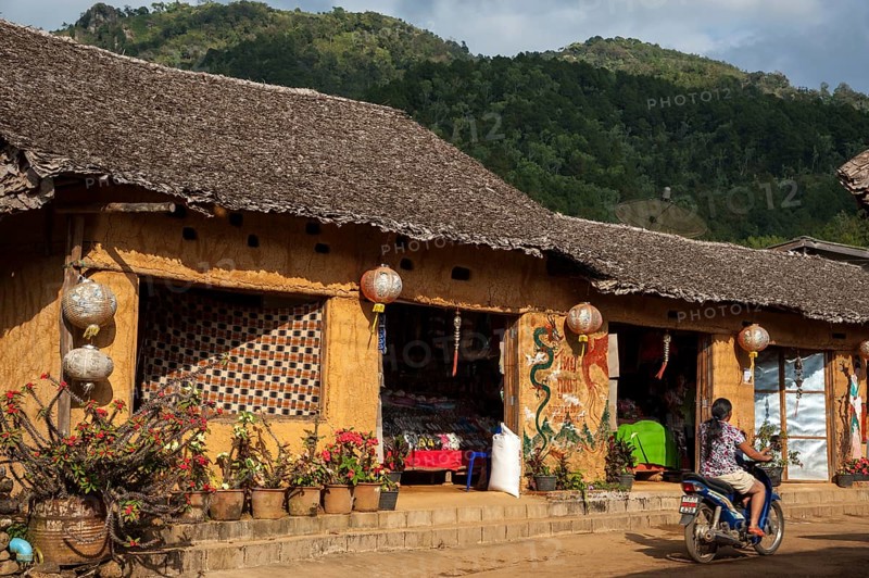 Woman riding a motorcycle in front of a tea shop in a village of the Chinese minority on the border with Myanmar