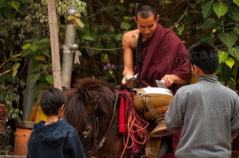 Buddhist monk on horseback with a begging bowl collecting alms in the morning