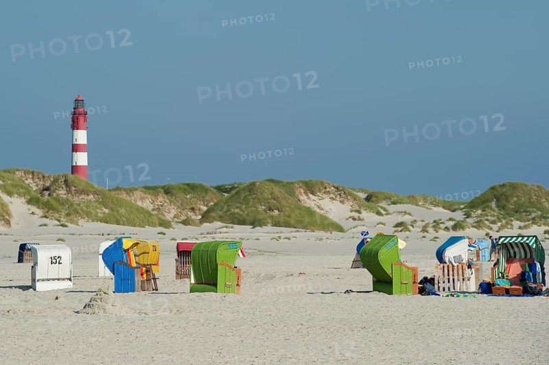 Roofed wicker beach chairs and lighthouse at Nebel