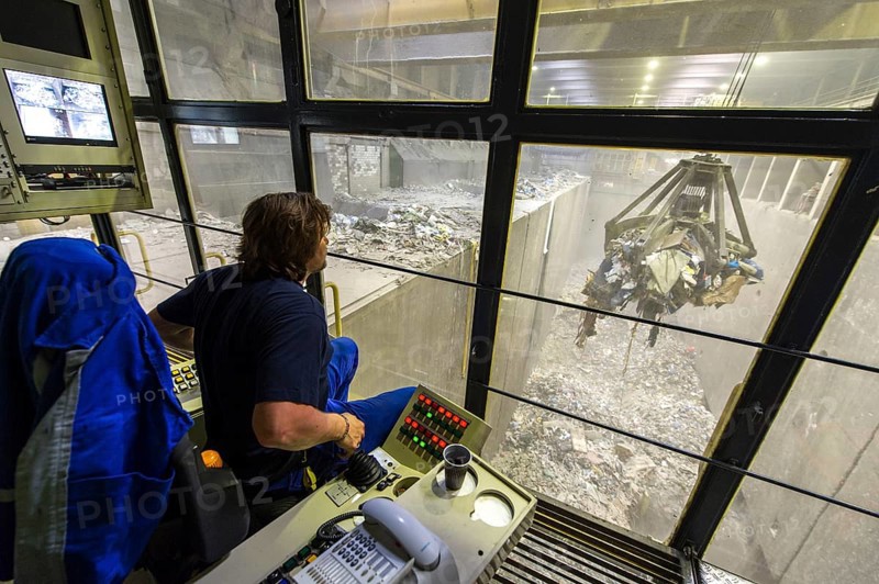 A crane operator is supervising the transport of waste to the incinerators in a waste incineration plant