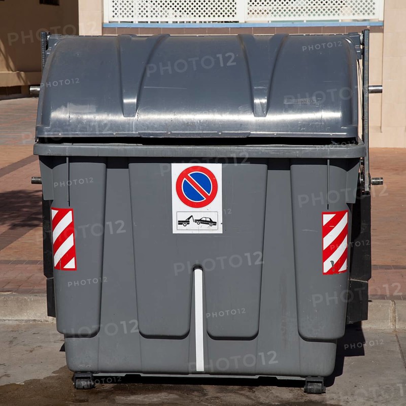 Wheeled trash can with a No parking sign standing on the roadside