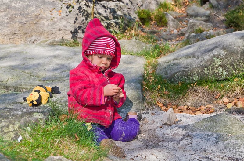 Little girl playing between rocks in the sand