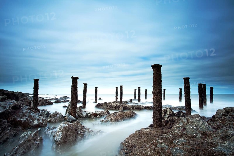 Steel stantions of ruined Victorian pier visable on shore at low tide
