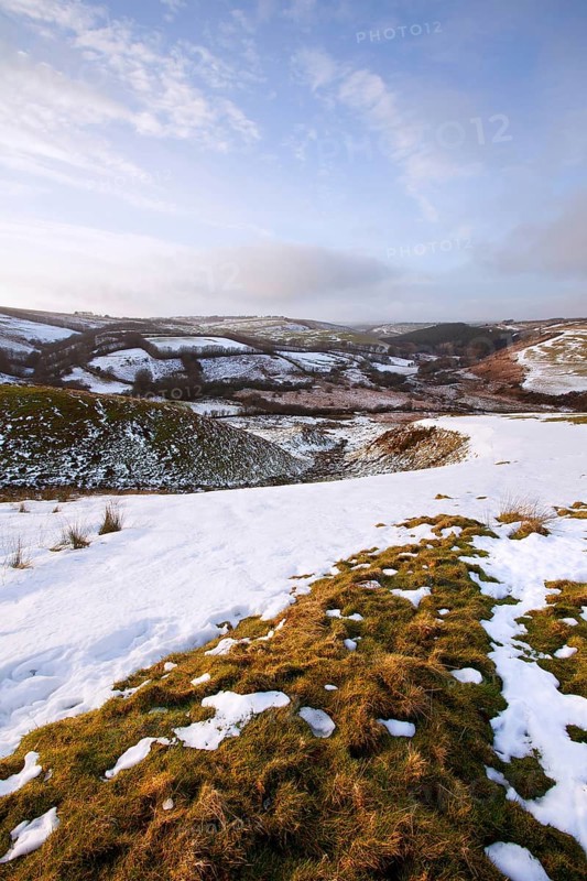 View of lingering snow on moorland hills and fields in late afternoon sunshine