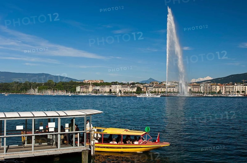 Ferry boat at the dock of the Geneva ferry company Mouettes genevoises in front of the giant fountain Jet d'Eau