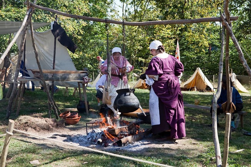 Women with a cooking pot over a campfire