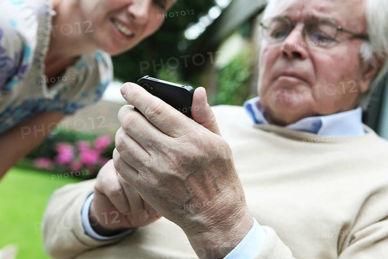 Young woman explaining to a senior citizen how to use a smartphone