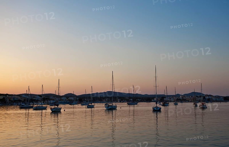Sailing boats in a harbour at sunset