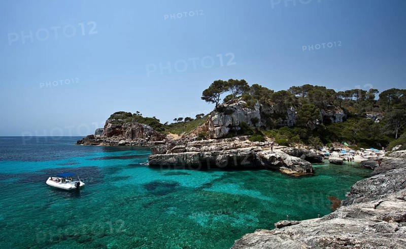 Boat in the rock-lined bay of Calo des Moro