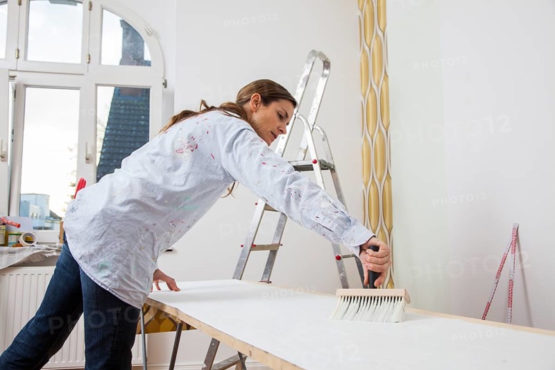 Young woman preparing wallpaper for wallpapering the walls