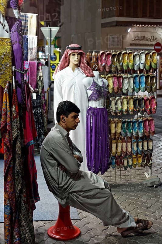 Salesman sitting bored in front of his shop