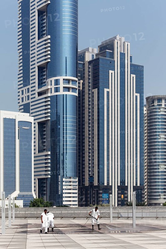 Workers cleaning a terrace in front of skyscrapers with a high pressure washer