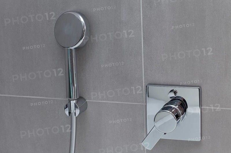 Modern shower head and bathroom fitting on tiled wall