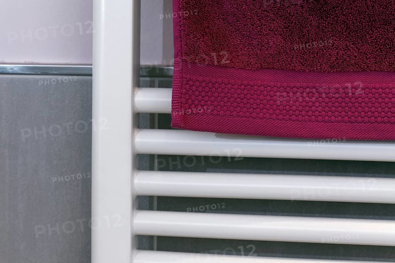 Berry-colored towel hanging on a radiator to dry