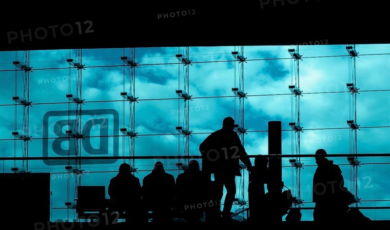 Silhouettes of travellers waiting for trains in the main station building