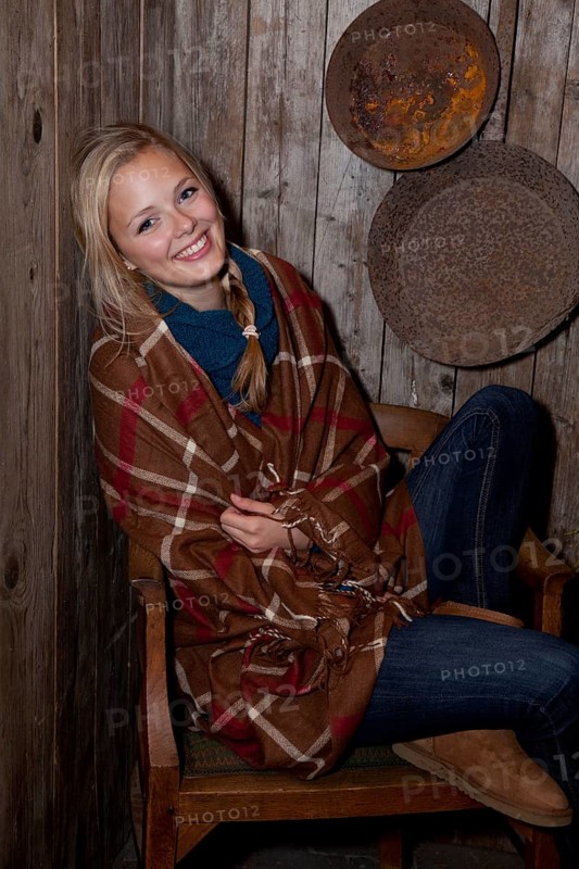 Smiling young woman wrapped in a blanket in a hiking hut