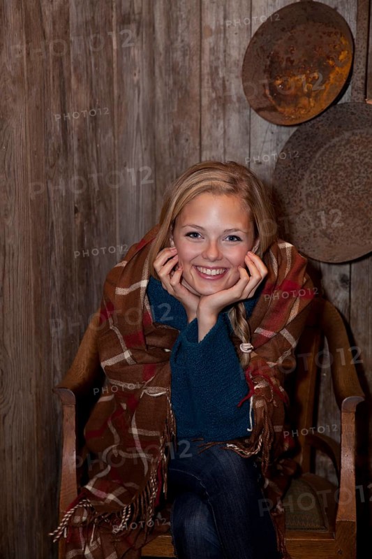 Smiling young woman wrapped in a blanket in a hiking hut