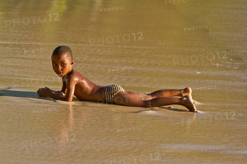 Creole boy lying on a beach