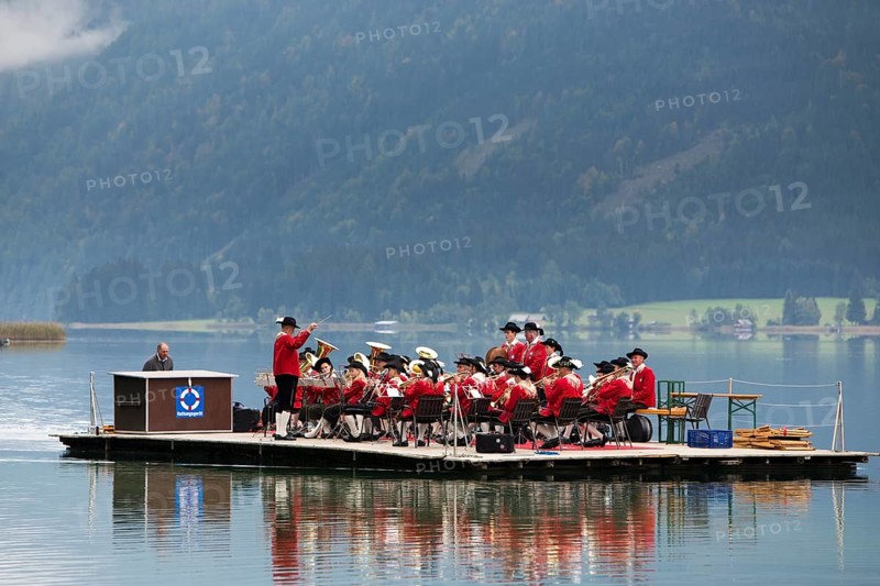 The Weissensee marching band in traditional costumes performing on a raft at the Naturparkfest festival in Techendorf