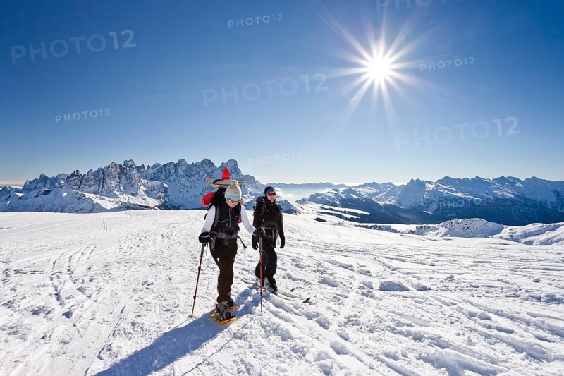 Snowshoe hiker and a cross-country skier ascending Uribrutto Mountain