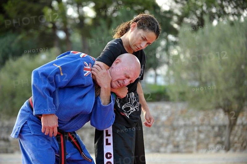 Student keeps her martial arts instructor in a headlock during a training session in a park