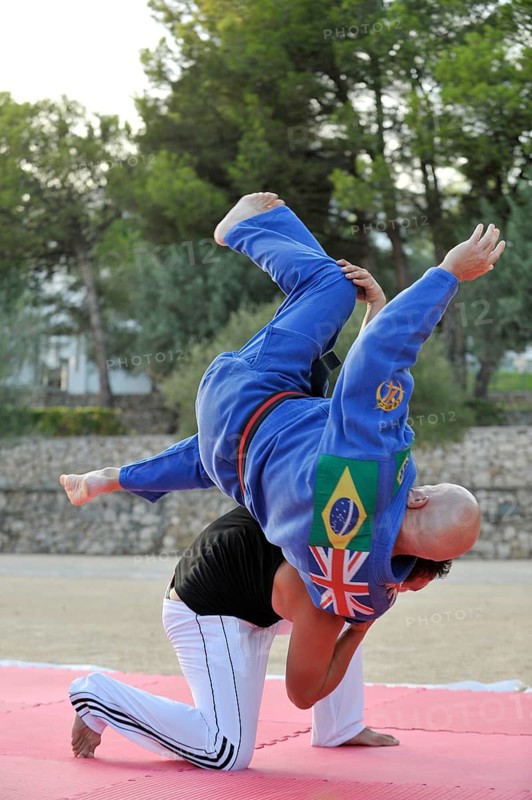 A martial arts instructor is demonstrating a shoulder throw with a student