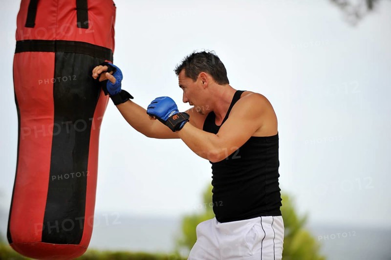 Man practicing punches on a punching bag in a park