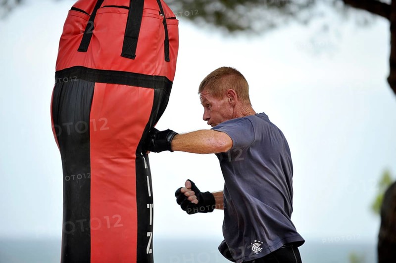Man practicing punches on a punching bag in a park