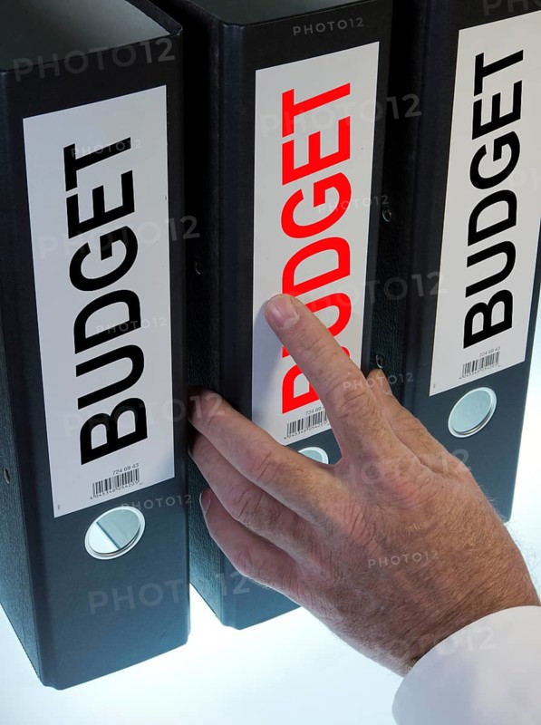 Hand reaching for a ring binder labelled 'BUDGET'