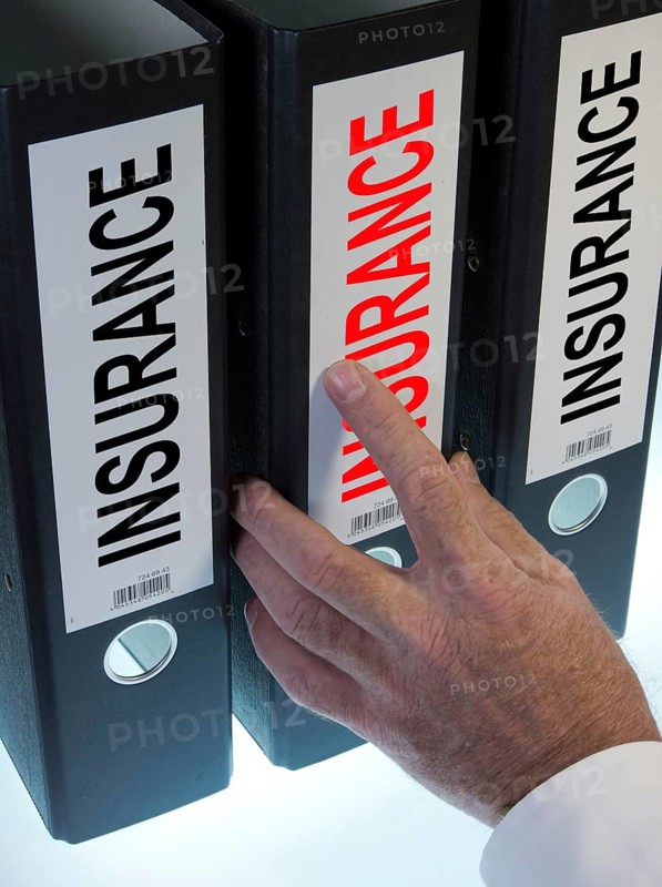 Hand reaching for a ring binder labelled 'INSURANCE'