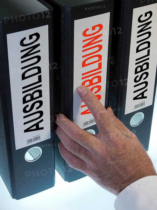 Hand reaching for a file folder labeled 'Ausbildung'