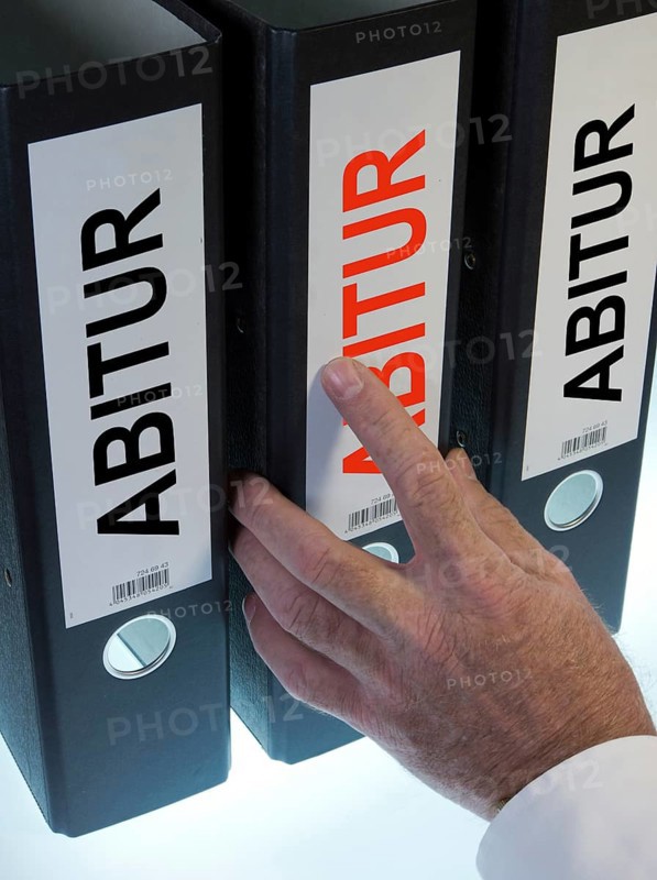 Hand reaching for a file folder labeled 'Abitur'