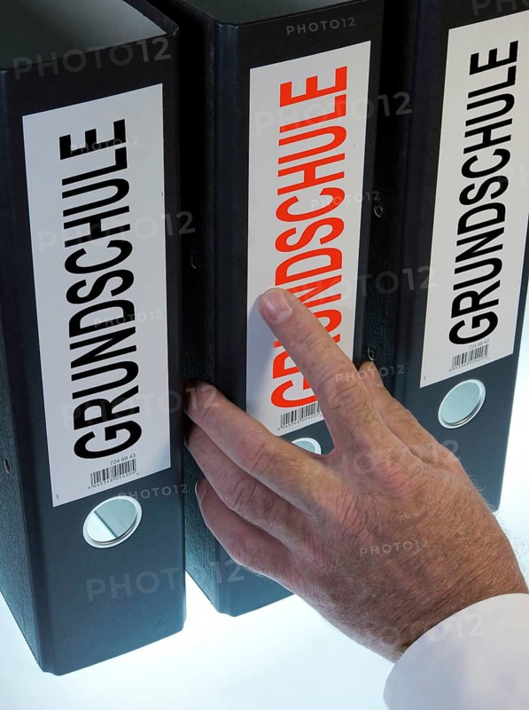 Hand reaching for a file folder labeled 'Grundschule'