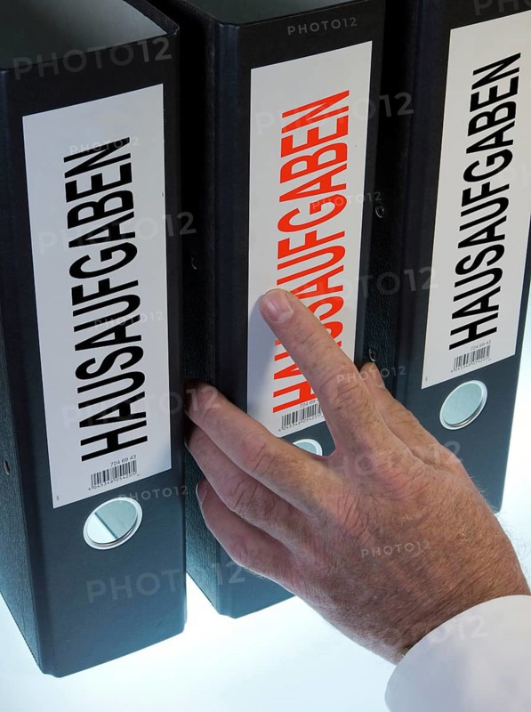 Hand reaching for a file folder labeled 'Hausaufgaben'