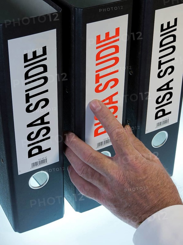 Hand reaching for a file folder labeled 'PISA-Studie'