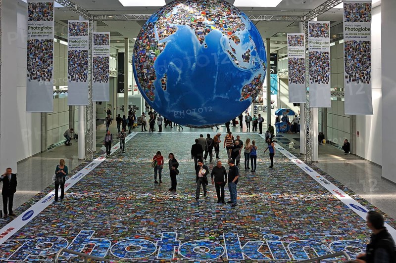 Installation depicting the global flood of images on a globe and on the floor in an exhibition hall