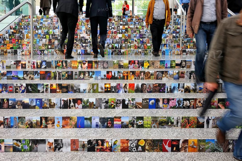 People walking on stairs covered with photos