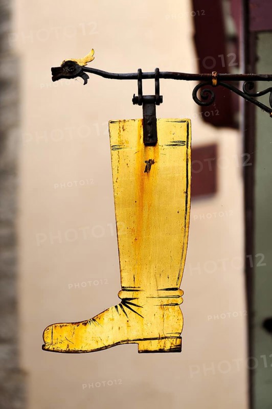 Gold-coloured boot as a hanging sign on a former shoemaker shop